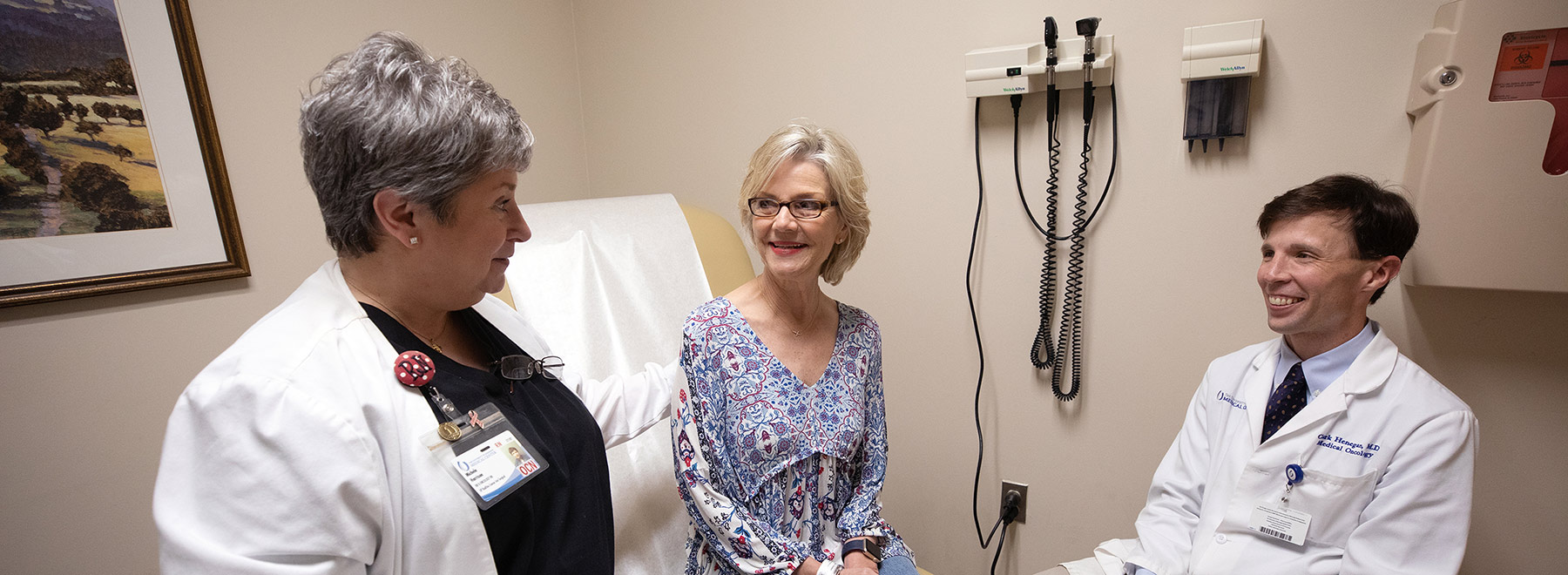 Two doctors talking to a patient in an exam room. Two doctors talking to a patient in an exam room.